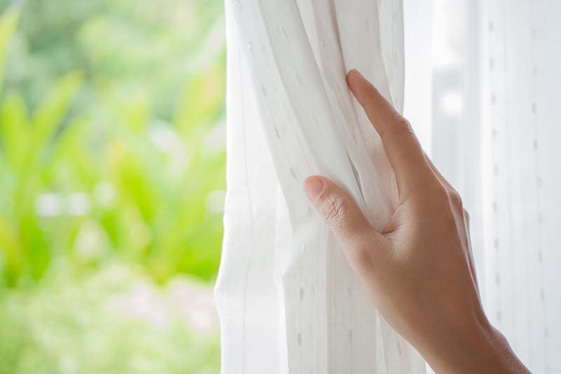 Homeowner looking at the spring weather outdoors to represent spring money saving tips.