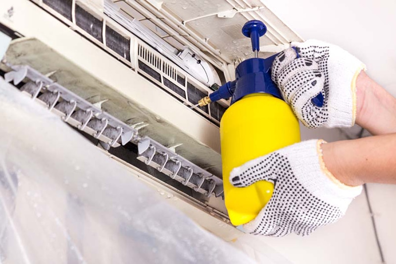 HVAC technician performing maintenance on a ductless AC unit.