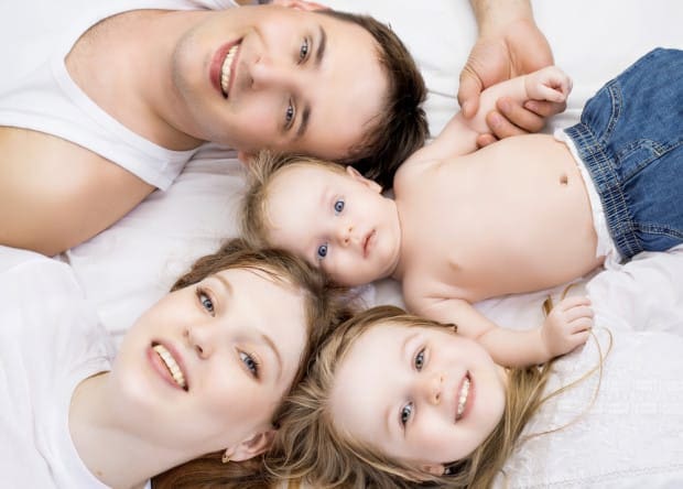 Family laying on bed, taking a selfie from above. Representing four reasons to have a humidifier in your home.