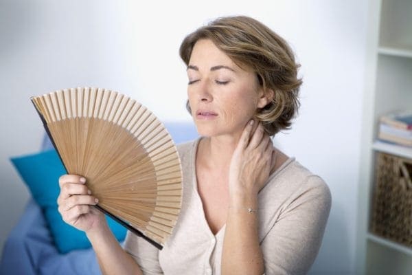 Woman fanning herself due to broken down air conditioner.