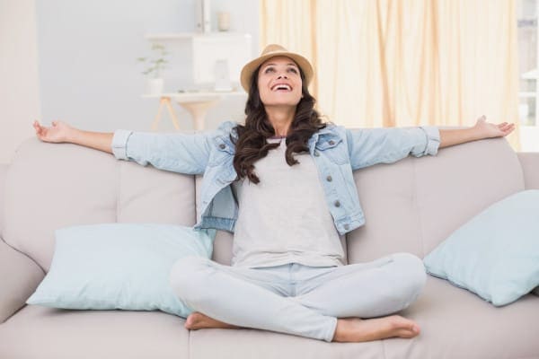 Happy female homeowner on couch after installing new indoor air quality technologies.
