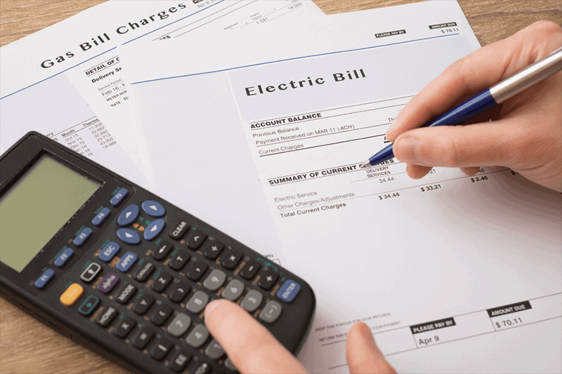 Business owner calculating electric bill to represent how to reduce your company's energy costs.