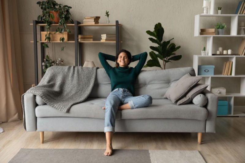 Woman enjoying her living room and indoor air quality after a whole-home humidifier installation.