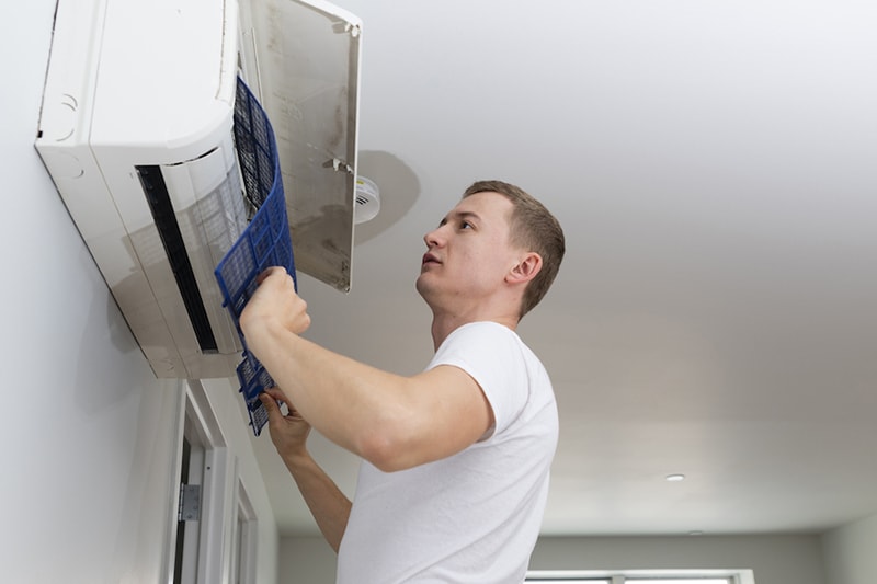 The Problem With Clogged Air Filters, The young man cleaning filters in the air-conditioning split device in the recently rented apartment in Brooklyn, New York, USA