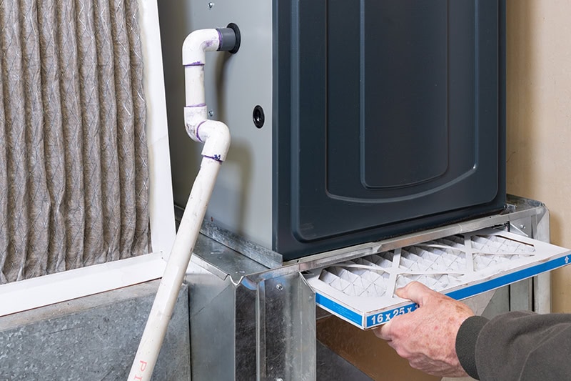 A dirty furnace filter is being replaced with a new furnace filter.