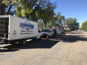 Winkelman Heating & Air Conditioning service vehicles lined up along residential street in Dumas, TX.