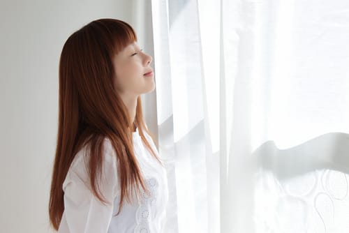 Woman breathing in fresh indoor air quality after learning how to improve it.