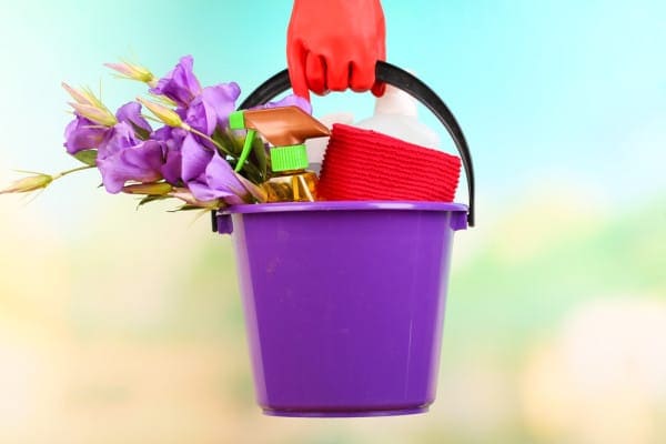 Cleaning supplies being held to represent spring cleaning and HVAC maintenance for better air quality.