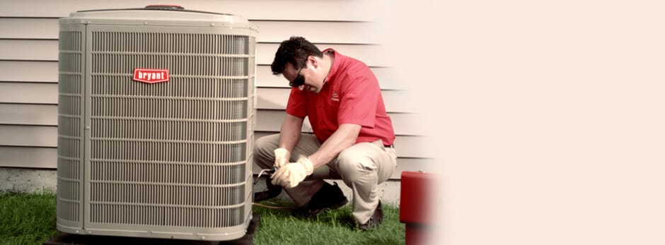 HVAC technician performing maintenance on Bryant heat pump.